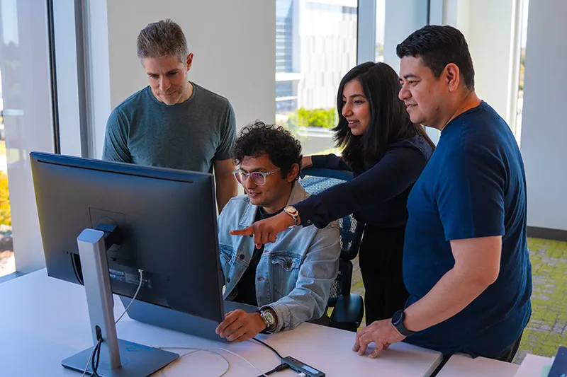 People engaged around a desktop monitor